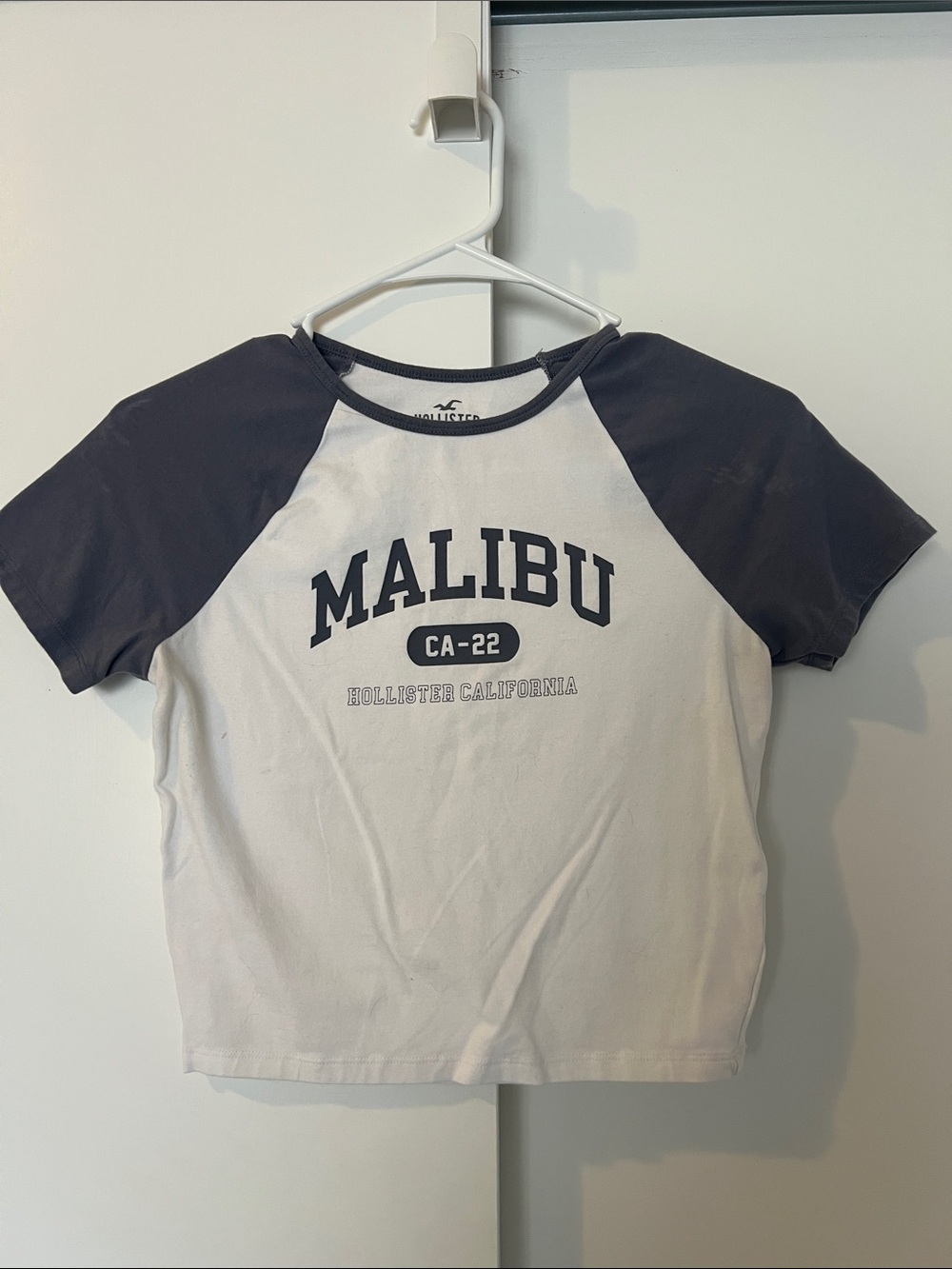 Hollister Cropped Baby Tee with Navy Raglan Sleeves and 'Malibu' Graphic